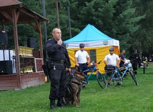 policjant z psem za nim 2 policjanci na rowerach