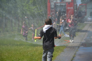 dziecko stoi w strugach wody z wozu strażackiego