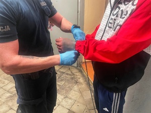 zatrzymany mężczyzna prowadzony przez umundurowanych policjantów