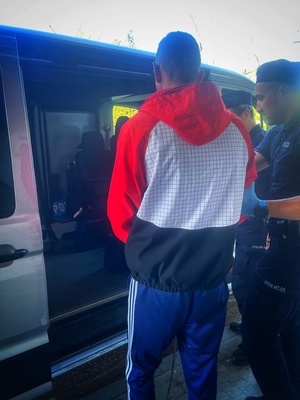 zatrzymany mężczyzna prowadzony przez umundurowanych policjantów