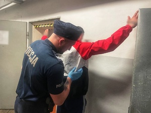 zatrzymany mężczyzna prowadzony przez umundurowanych policjantów