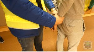 Policjant zakłada kajdanki podejrzanemu o włamanie do pojazdu.