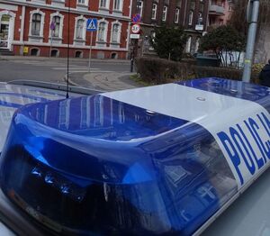 na zdjęciu radiowóz policyjny na tle budynków/sklepów.