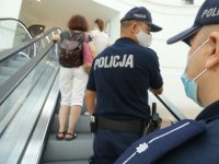Policjanci umundurowani prowadzą kontrolę w sklepach wielkopowierzchniowych w związku z obowiązkiem zasłaniania ust i nosa