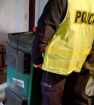 Policjant w odblaskowej kamizelce przy piecu grzewczym