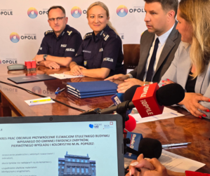 Komendant Wojewódzki Policji w Opolu oraz Komendant Miejski Policji w Opolu, w umundurowaniu, i przedstawiciele władz miasta podczas podpisywania umowy na przekazanie dotacji