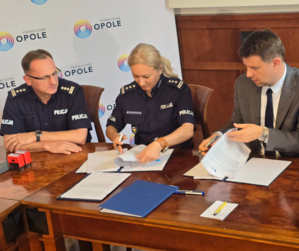 Komendant Wojewódzki Policji w Opolu oraz Komendant Miejski Policji w Opolu, w umundurowaniu, i przedstawiciele władz miasta podczas podpisywania umowy na przekazanie dotacji