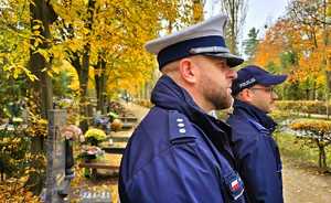 Zdjęcie przedstawia policjanta na cmentarzu.