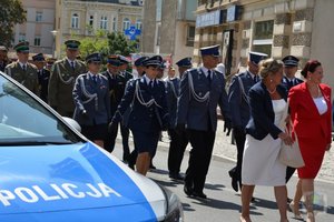 Policjanci z pocztu sztandarowego maszerują ulicami miasta. Na zdjęciach widać policjantów idących w szeregach