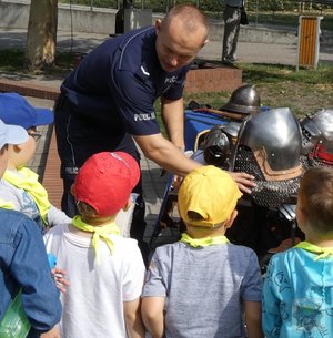 na pikniku policyjnym: dzieci biorą udział w kole fortuny - konkursie z nagrodami - policjant-rycerz pokazuje zbroje, policjant-malarz pokazuje swoje obrazy, komandosi policyjni prezentują uzbrojenie