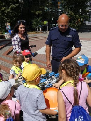 dzieci przy radiowozie oglądają policyjny sprzęt, inna gromadka dzieci ogląda miniaturki radiowozów